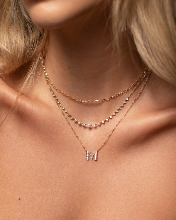 14k yellow gold mini link necklace, diamond station chain necklace, and letter M diamond pendant necklace shown on model