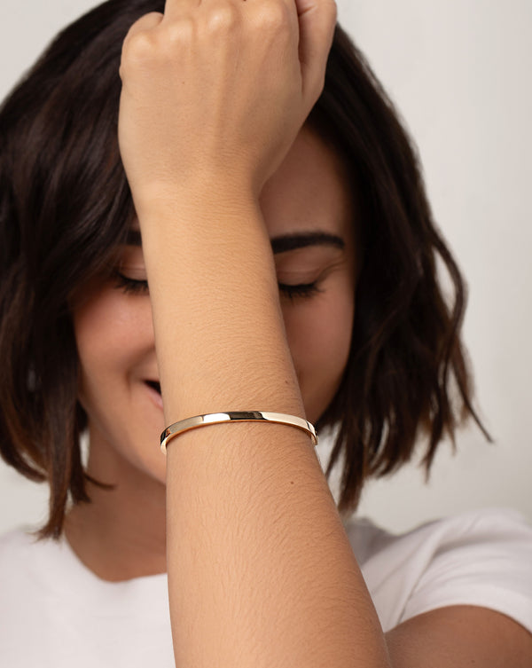 Stackable Gold Bangle on models wrist with hand in front of face