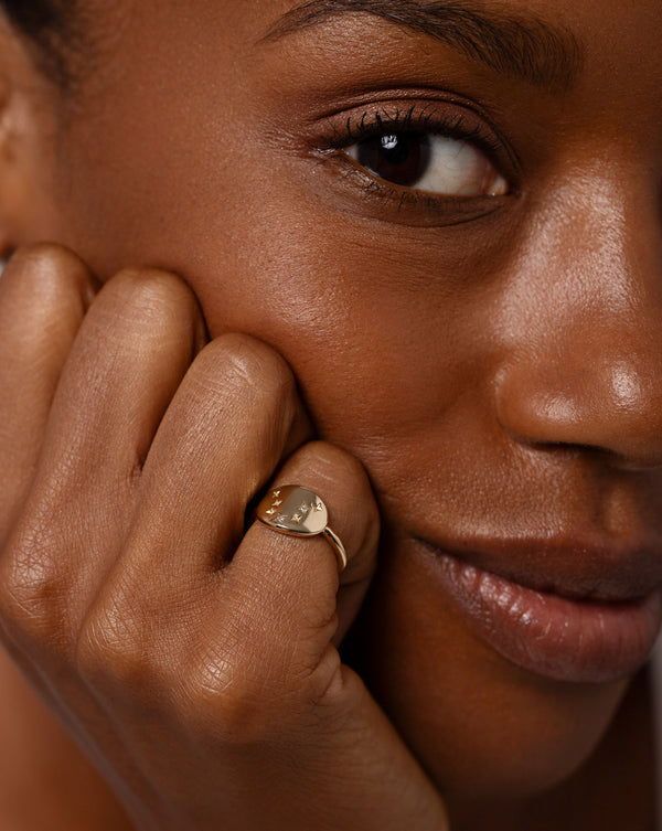 Zodiac Constellation Signet Ring worn on pinky of hand resting on face of model