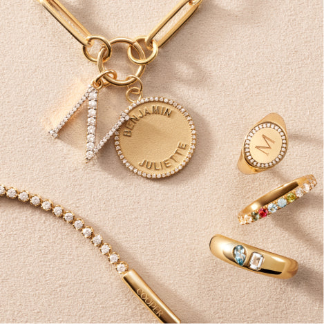 various personalizable pendants and rings against a travertine background