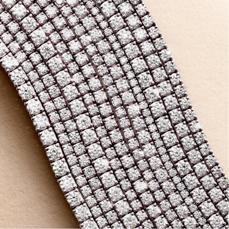 stacked diamond tennis bracelets and necklaces against a travertine background