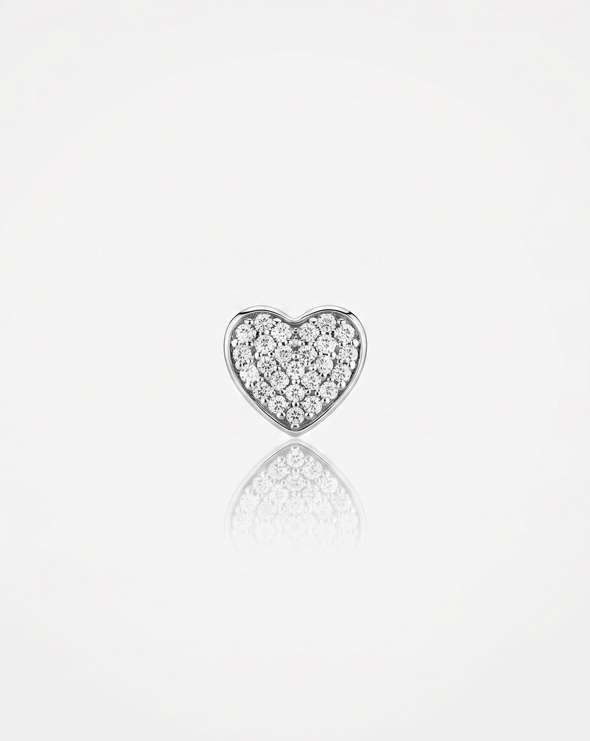A small heart-shaped silver stud earring paved with diamonds, centered on a reflective white surface.