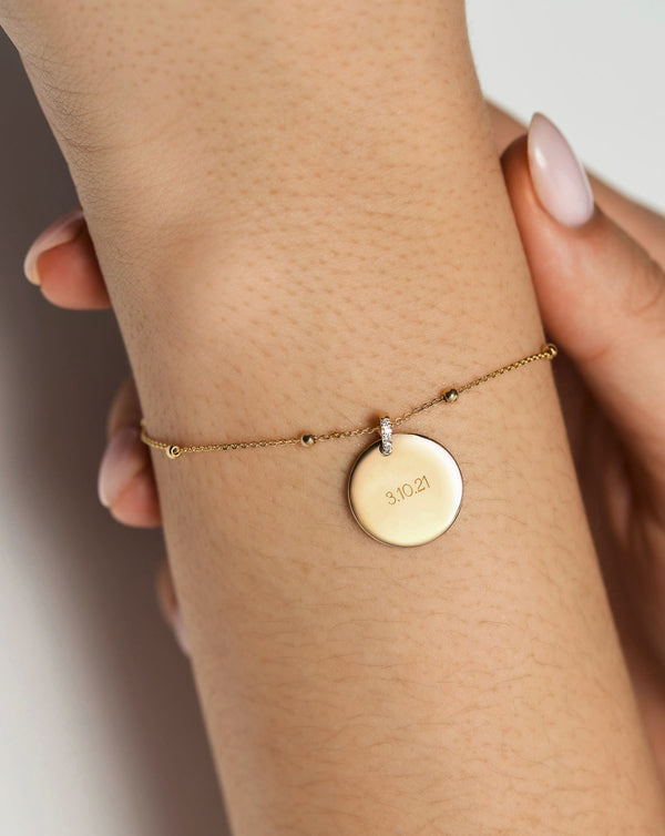 Model wearing Yellow Gold Engravable Round Pendant added to Yellow Gold Saturn Chain Bracelet.