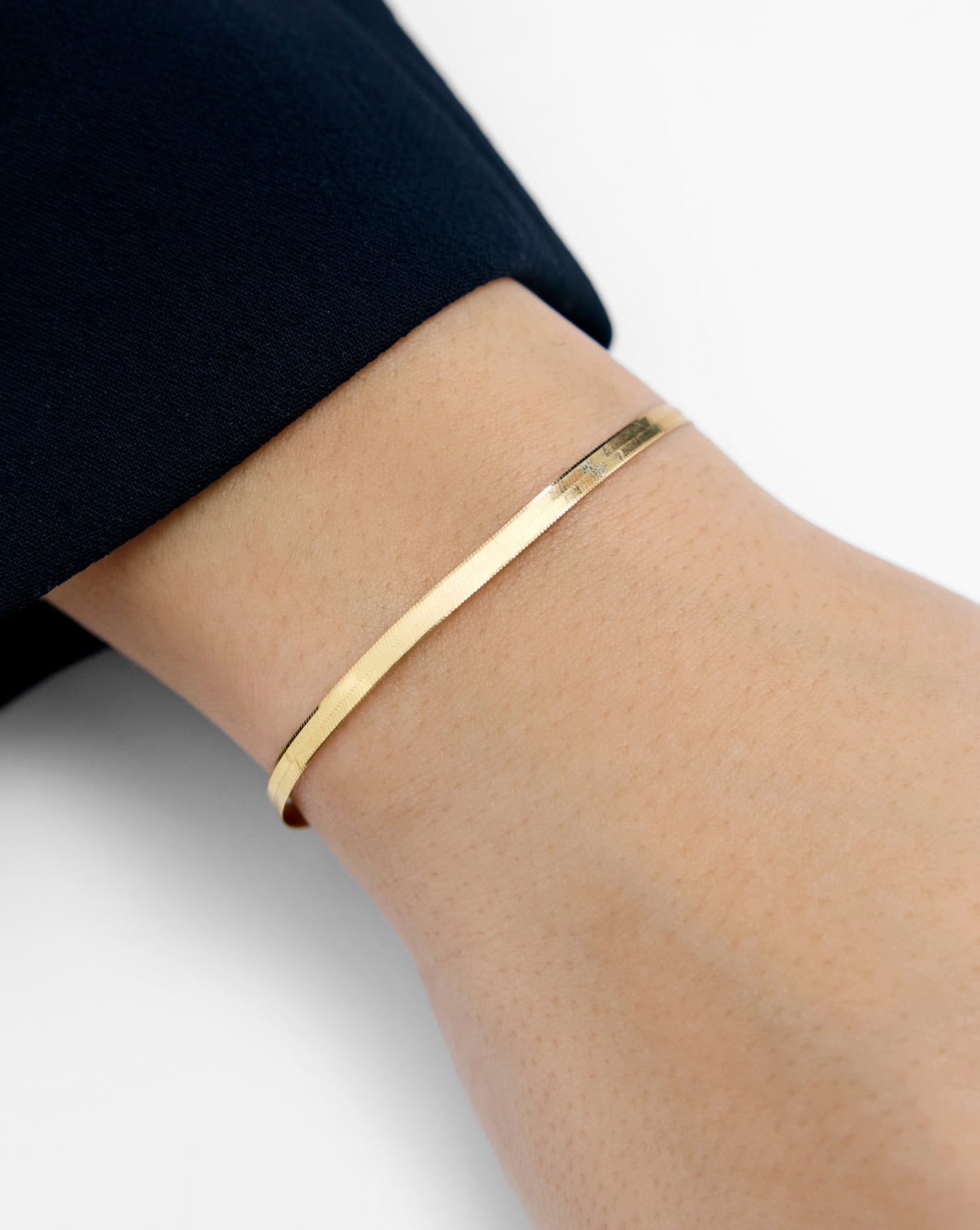 Gold herringbone bracelet worn by model highlighting luxurious appeal global