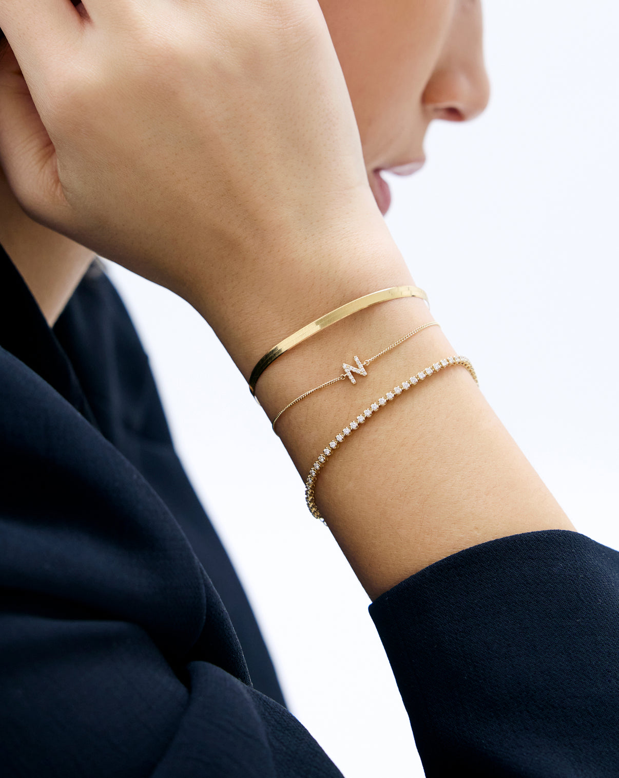 Gold herringbone bracelet worn by model with other best selling bracelets