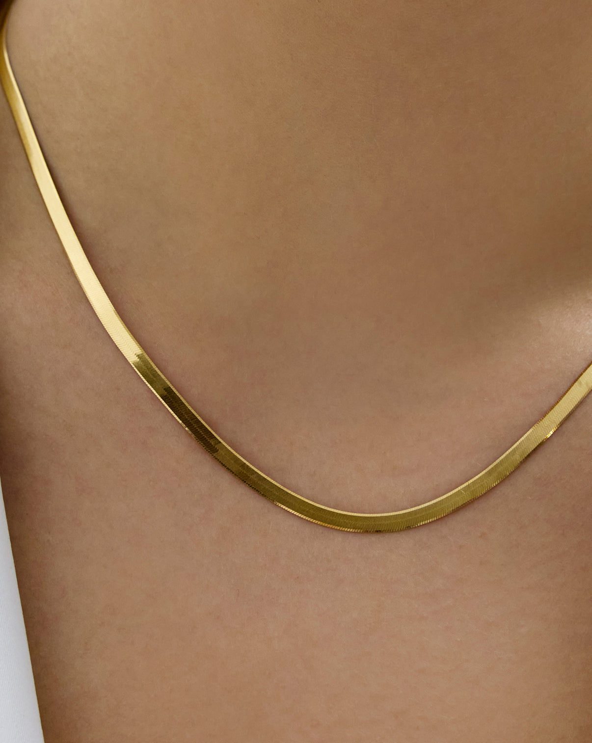 Close-up detail of herringbone chain necklace showing flat woven texture global