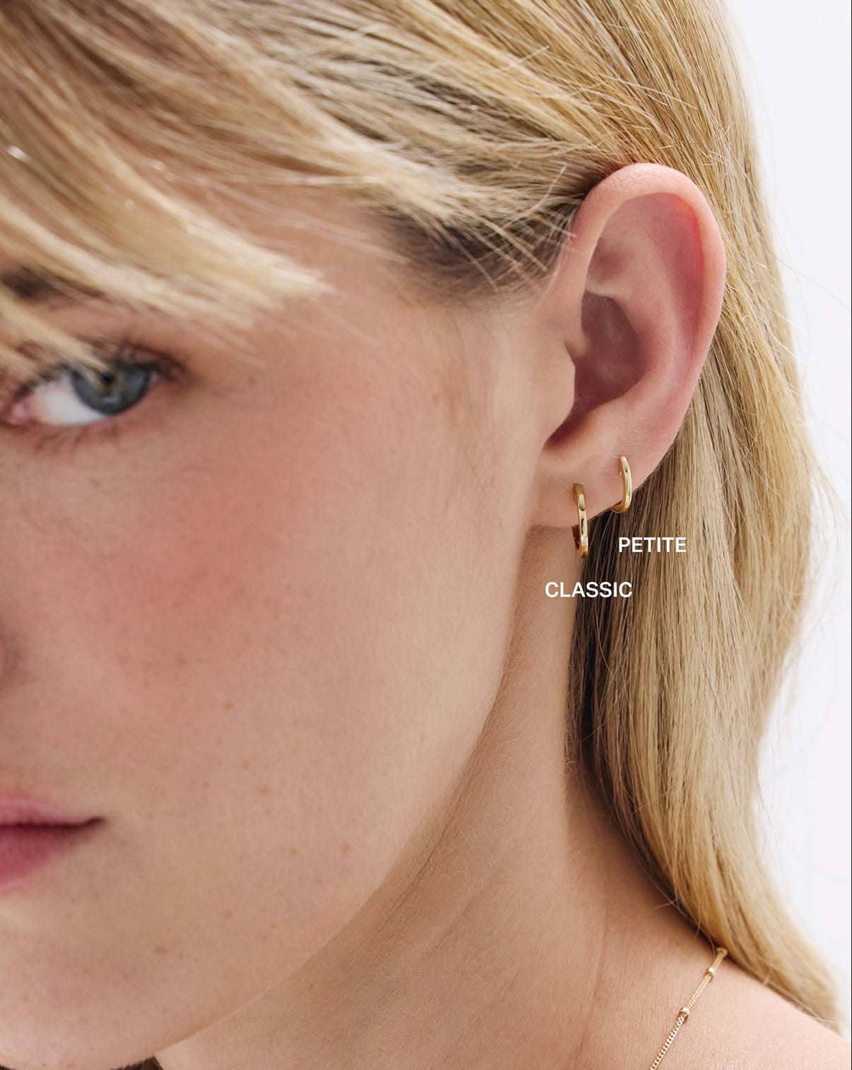 Petite and Classic sized Gold Huggies earrings shown on model's ear