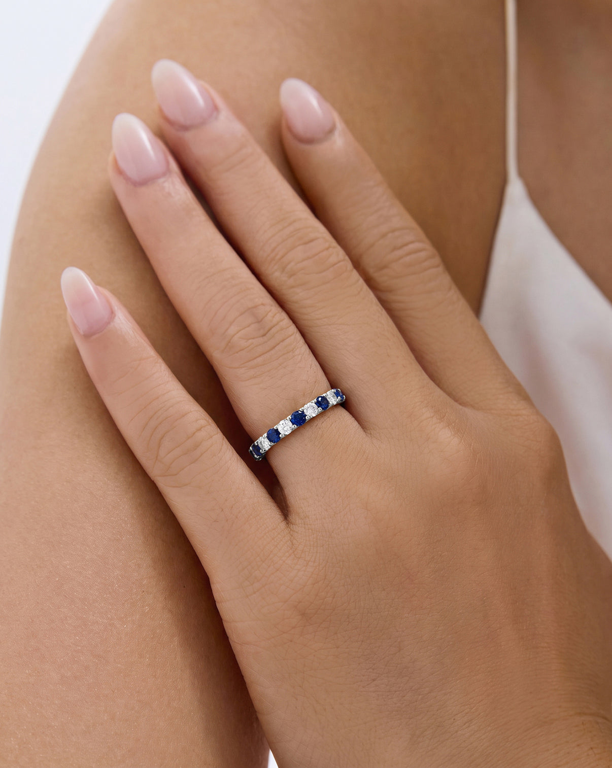 A close-up of a hand wearing the Classic Sapphire and Diamond wedding band