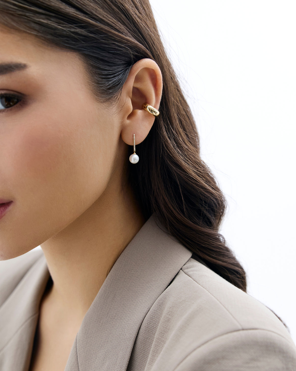 Model wearing Diamond and Pearl Drop Earrings in 14K Yellow Gold styled with additional gold earring.