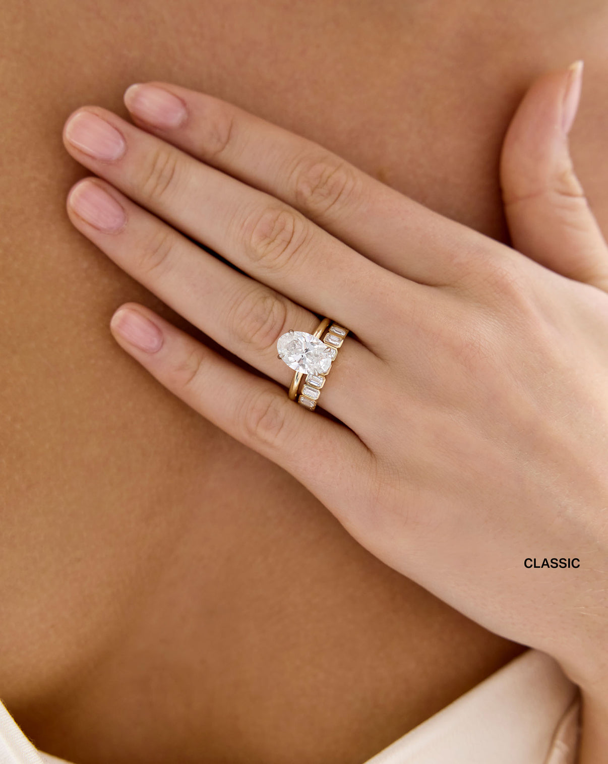 model wearing classic 3 carat weight Diamond Emerald Bezel Band ring in 14K Yellow Gold stacked with Oval Engagement Ring set in Whisper Thin global