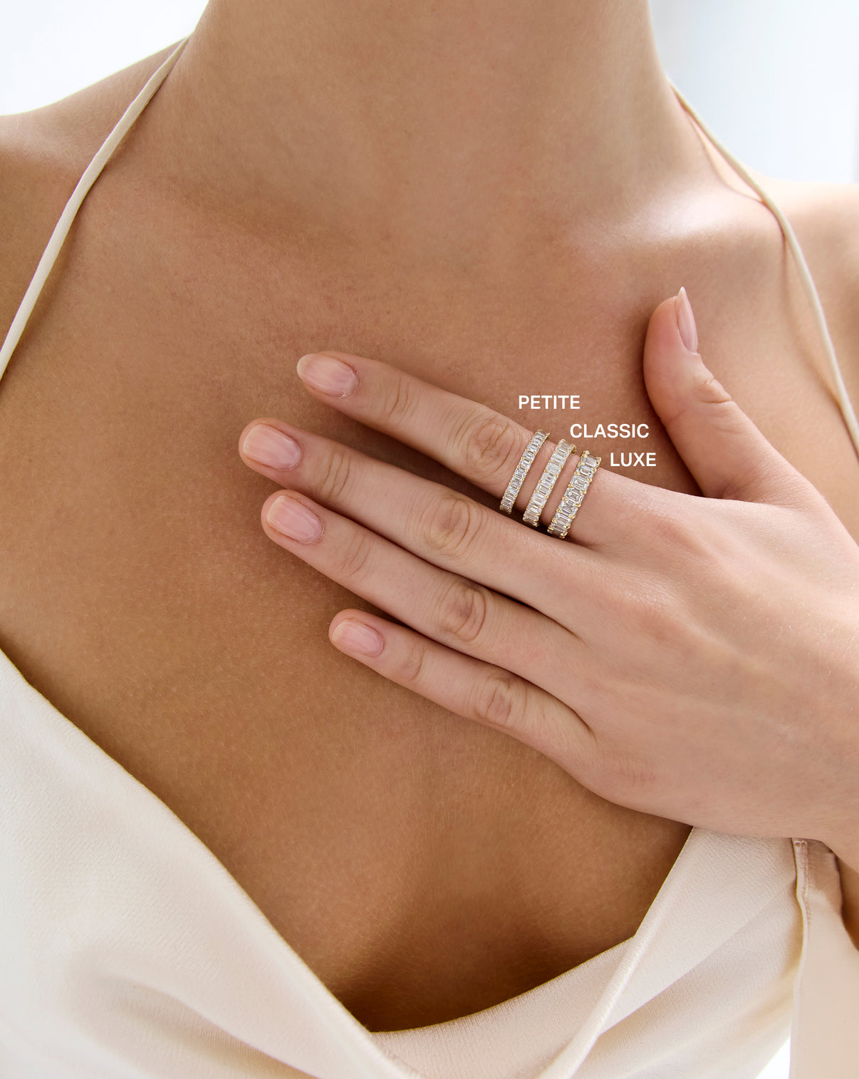 model wearing 3 sizes of the emerald diamond eternity band; petite, classic, and luxe in order from smallest to largest carat weight global