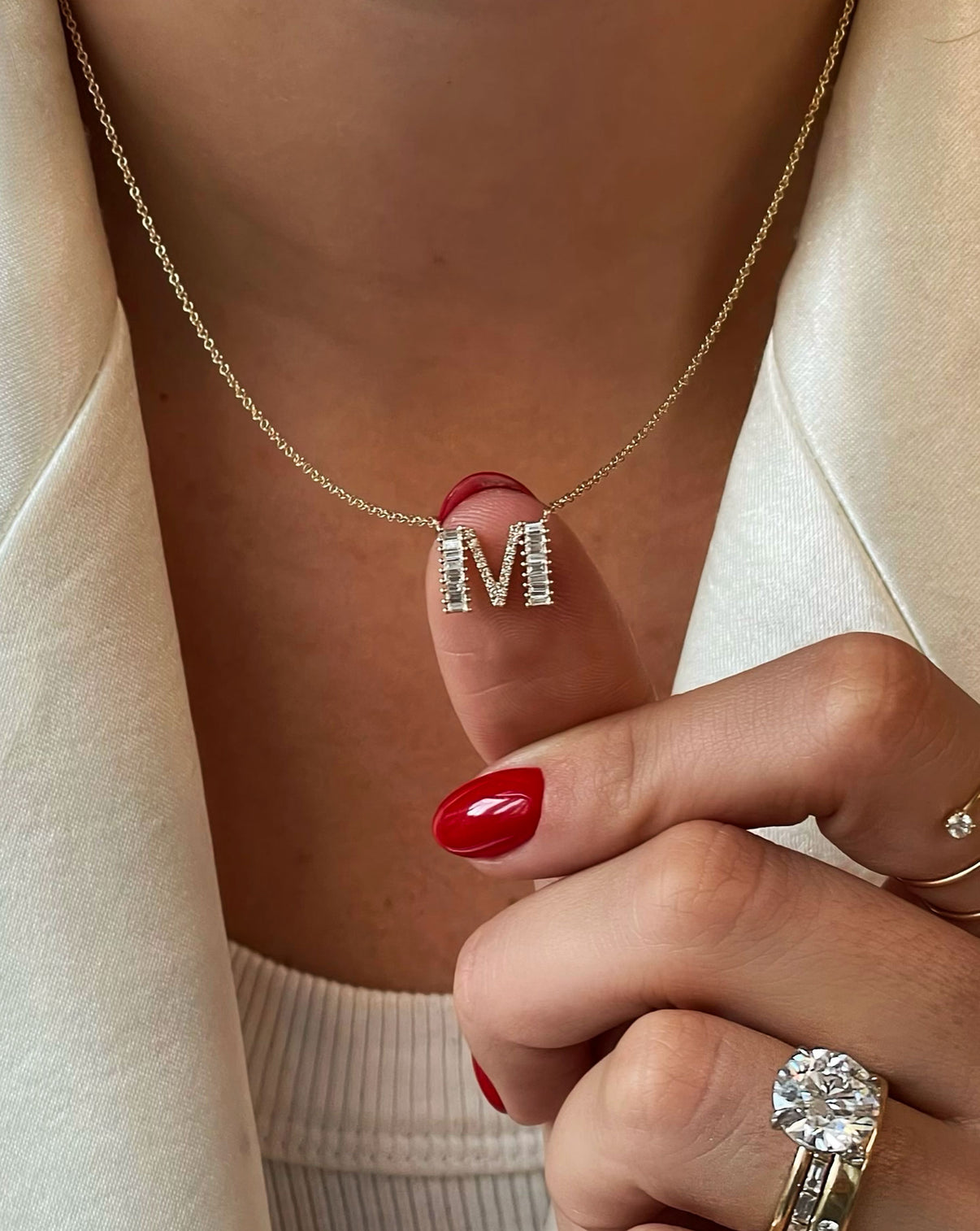 Model touching the Baguette + Pavé Initial Necklace letter M around her neck