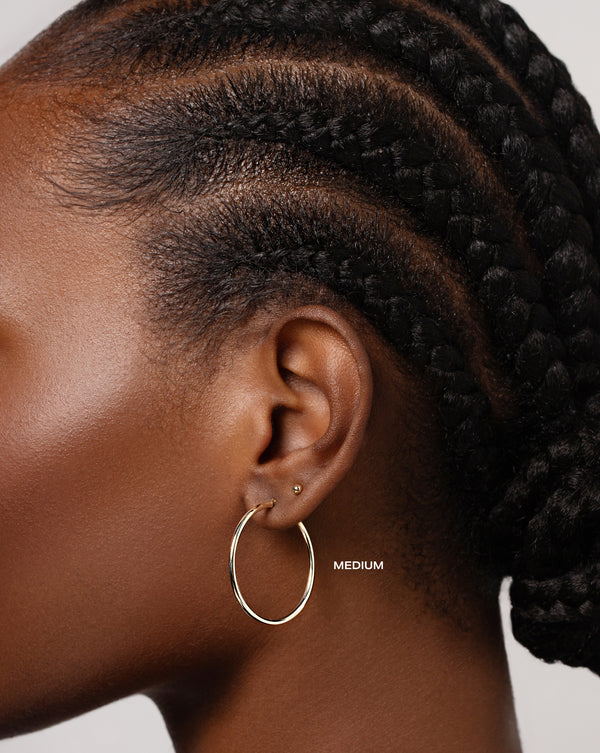 2 mm Gold Tube Hoops size medium shown on ear of model with the Petite Gold Studs