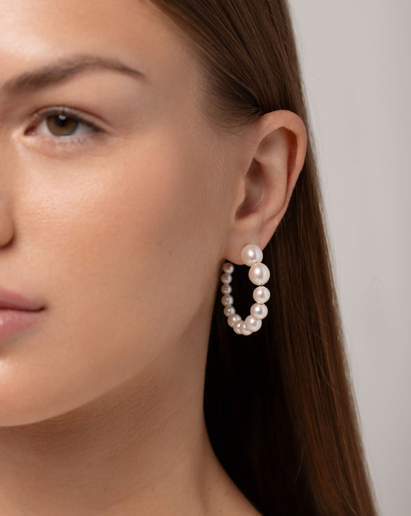 Graduated Pearl Hoops size large on ear of model facing forward