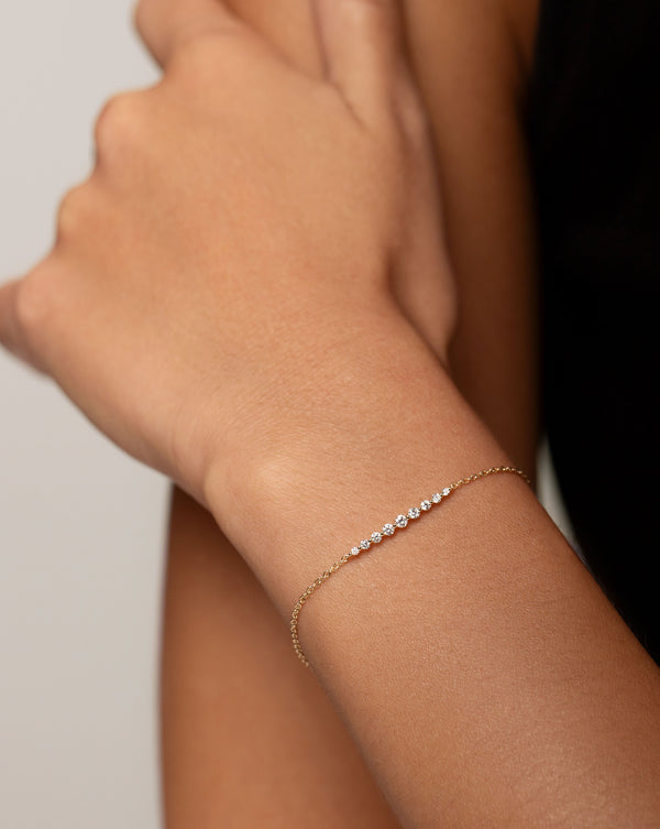 Graduated Single Prong Diamond Bracelet in 14kt yellow gold shown on model's wrist with hand touching shoulder