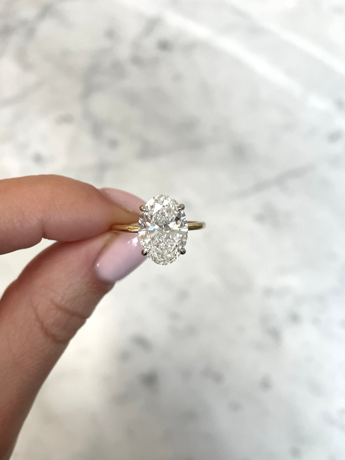 4ct oval cut diamond in our whisper thin yellow gold with platinum prongs
