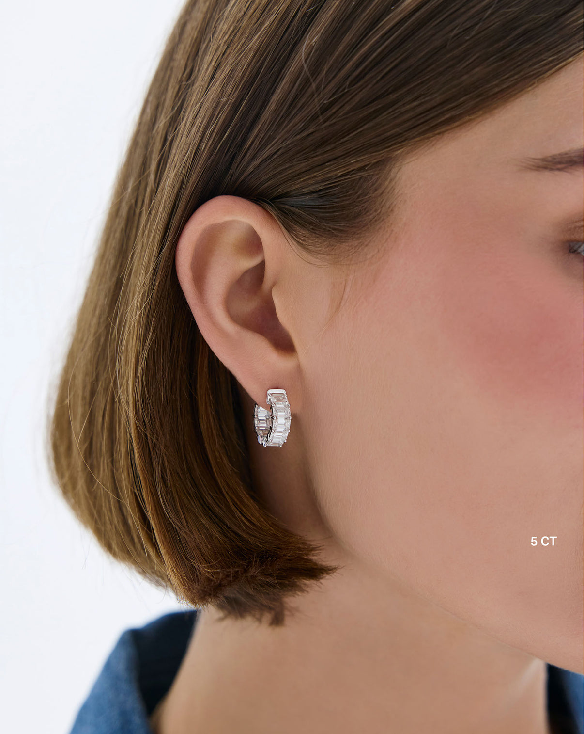 Close-up of model wearing white gold emerald lab 5 carat diamond huggie earrings in white gold - Ring Concierge global