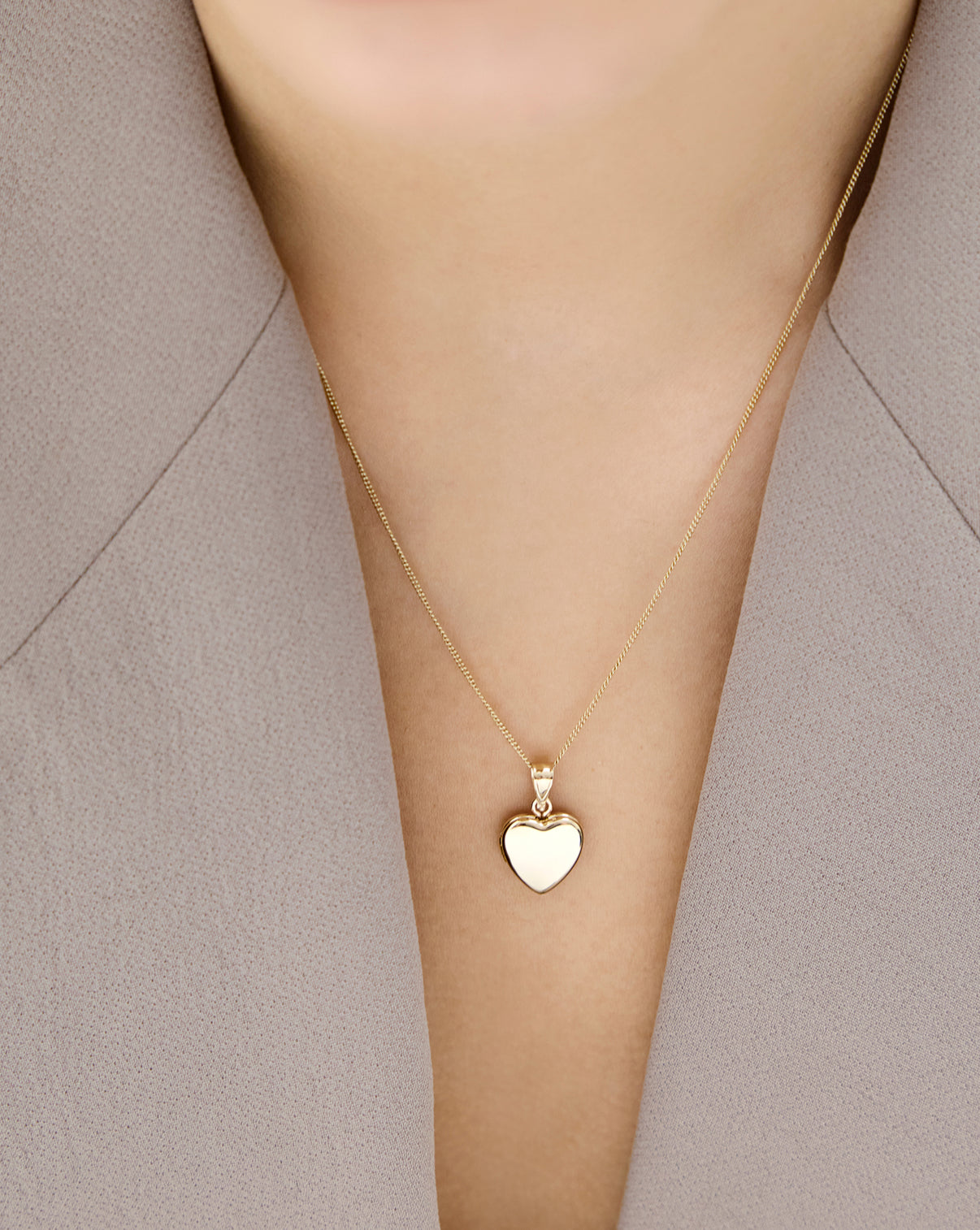 Close-up of Mini Heart Locketand diamond cut curb chain necklace in 14k yellow gold worn on model global