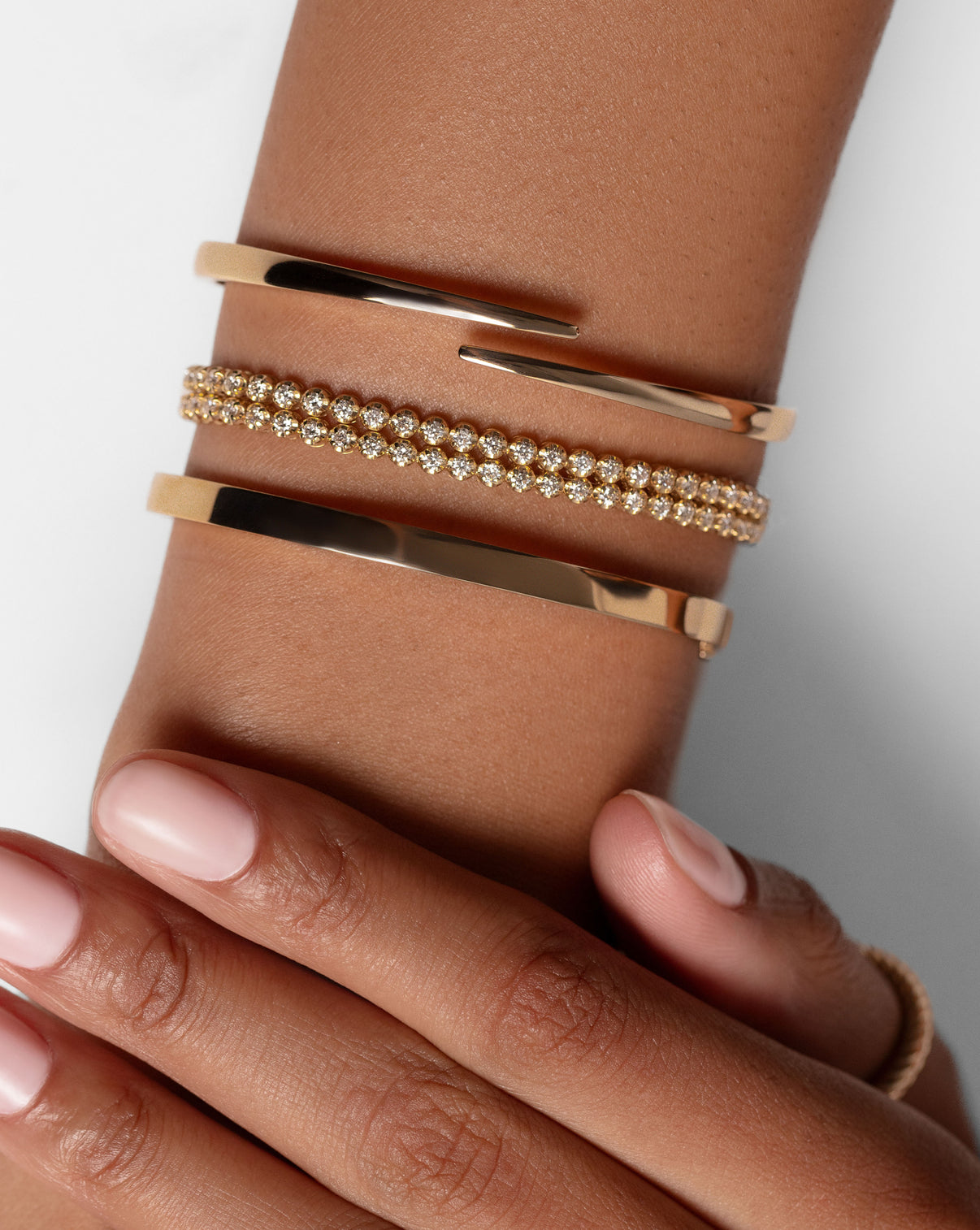 Open Gold Wrao Bangle shown on with the Stackable Gold Bangle and Multiway Tennis + Double Wrap Bracelet on wrist