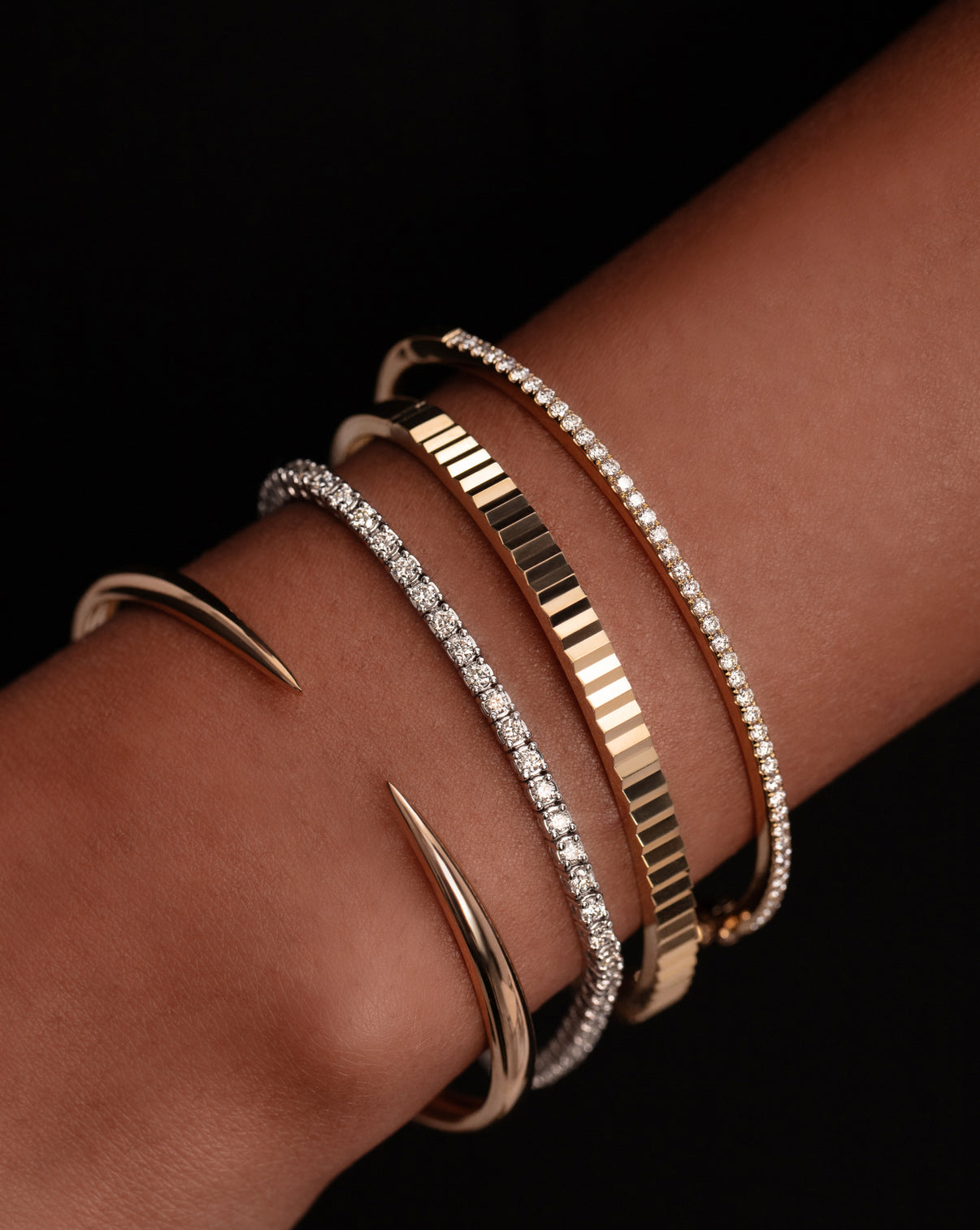 classic diamond bangle, fluted gold bangle, classic diamond tennis bracelet, and gold claw cuff on model