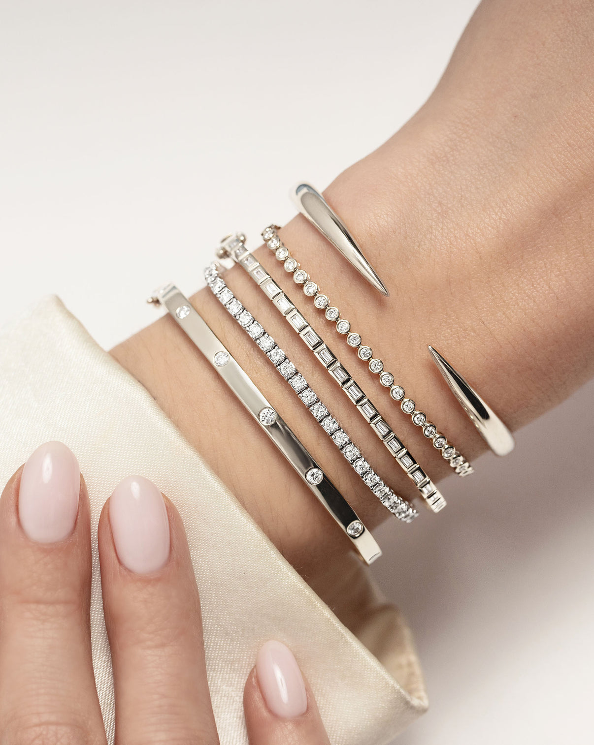 Gold Claw Cuff in white gold styled with other diamond and gold bracelets on model