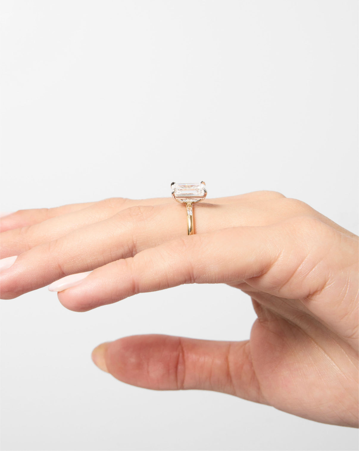 side view of 3 carat Emerald Diamond Engagement Ring in Yellow Gold Cloud Three Stone with Baguettes on model's hand