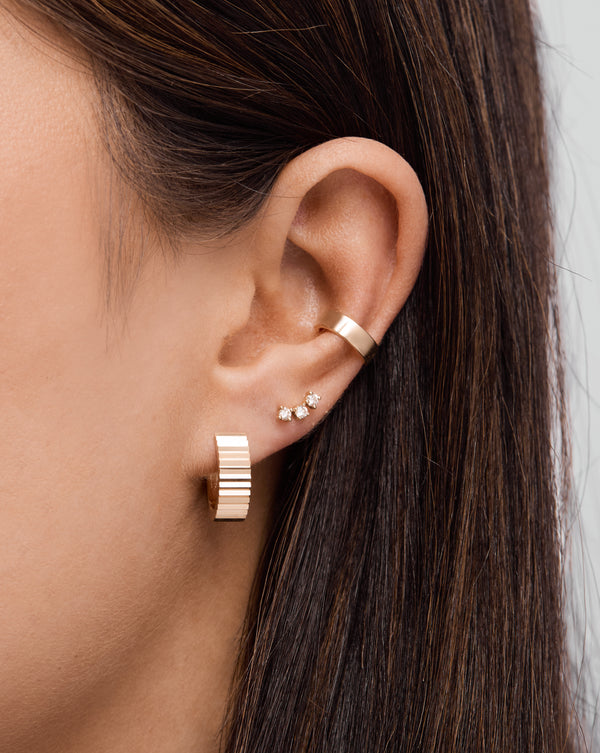 Wide Fluted Gold Hoop, Curved Trio Stud, and Bold Gold Flat Ear Cuff styled on model's ear.