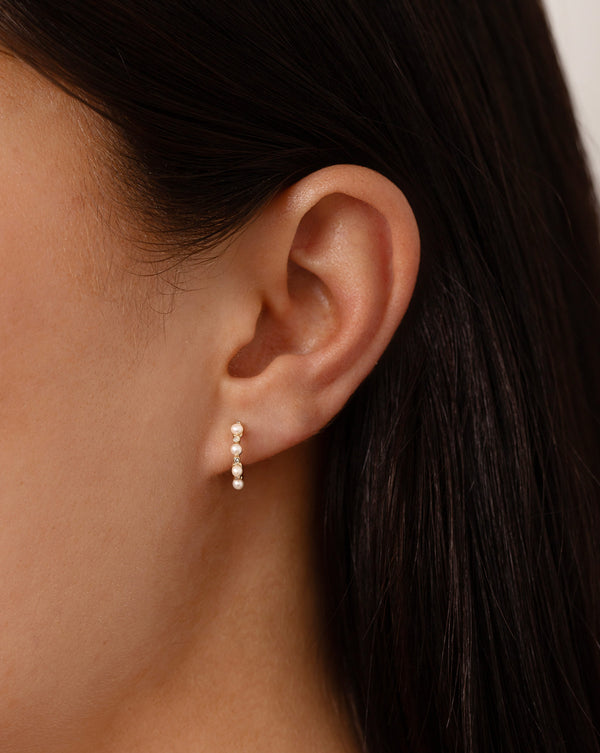 Pearl + Diamond Huggies shown on ear of model