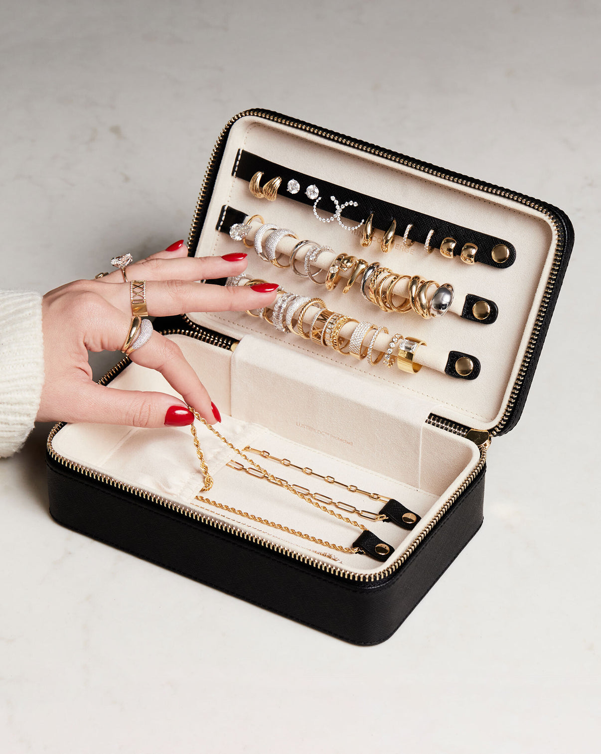 Multiway Leather Jewelry Case shown open storing jewelry with model touching a necklace wearing the Gold Cloud Ring, Pave Movement Cloud Ring, Diamond Personalized Roman Numeral Ring, Diamond Signet Pinky Ring and a Toi et Moi Engagement Ring