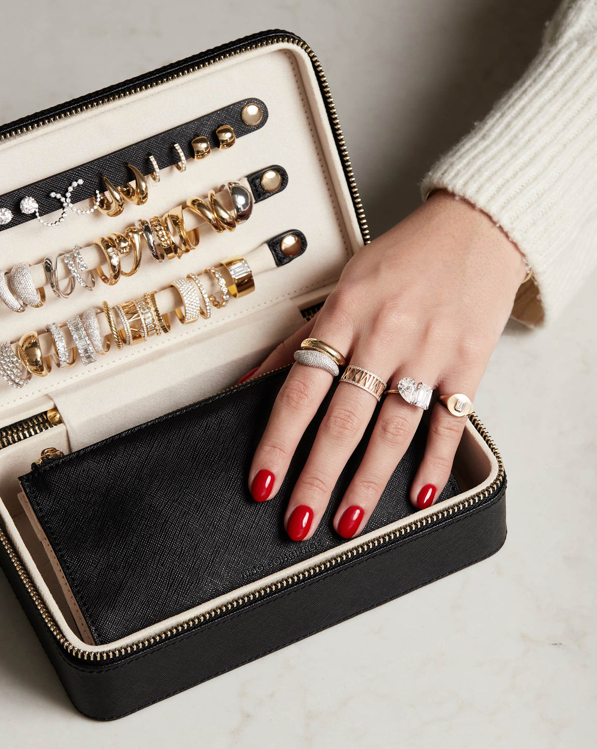Multiway Leather Jewelry Case shown open storing jewelry with model holding onto the removable leather pouch while wearing the Gold Cloud Ring, Pave Movement Cloud Ring, Diamond Personalized Roman Numeral Ring, Diamond Signet Pinky Ring and a Toi et Moi Engagement Ring