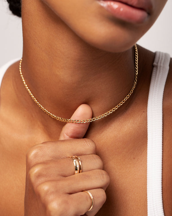 Multiway Curb Chain Necklace + Double Wrap Bracelet around neck of model with thumb touching necklace. Model is also wearing the Scattered Luxe Inlay Eternity Band and Single baguette Diamond Ring 