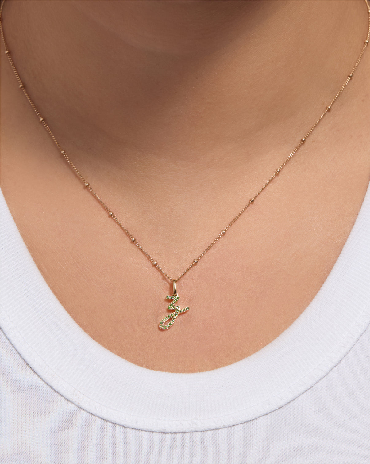 Gemstone Script Initial Pendant in green tsavorite styled on a chain on model