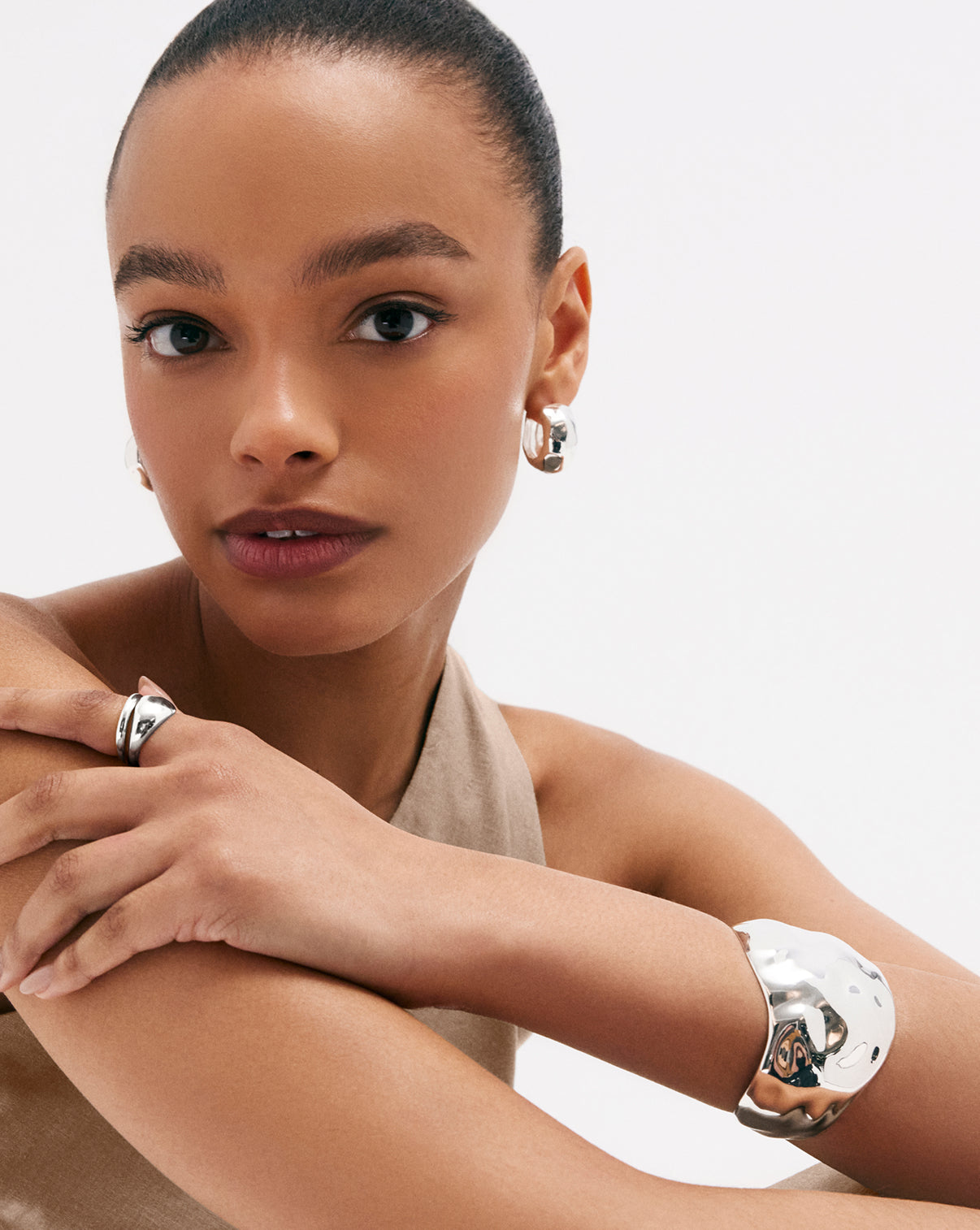 Model wearing sterling silver hammered bangle bracelet, styled with other silver jewelry pieces for layered look