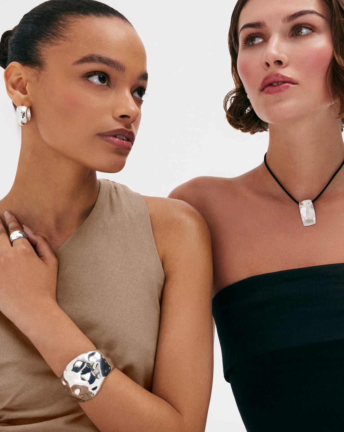 Models wearing sterling silver hammered bangle bracelet hoops and necklace, styled with other silver jewelry pieces for layered look