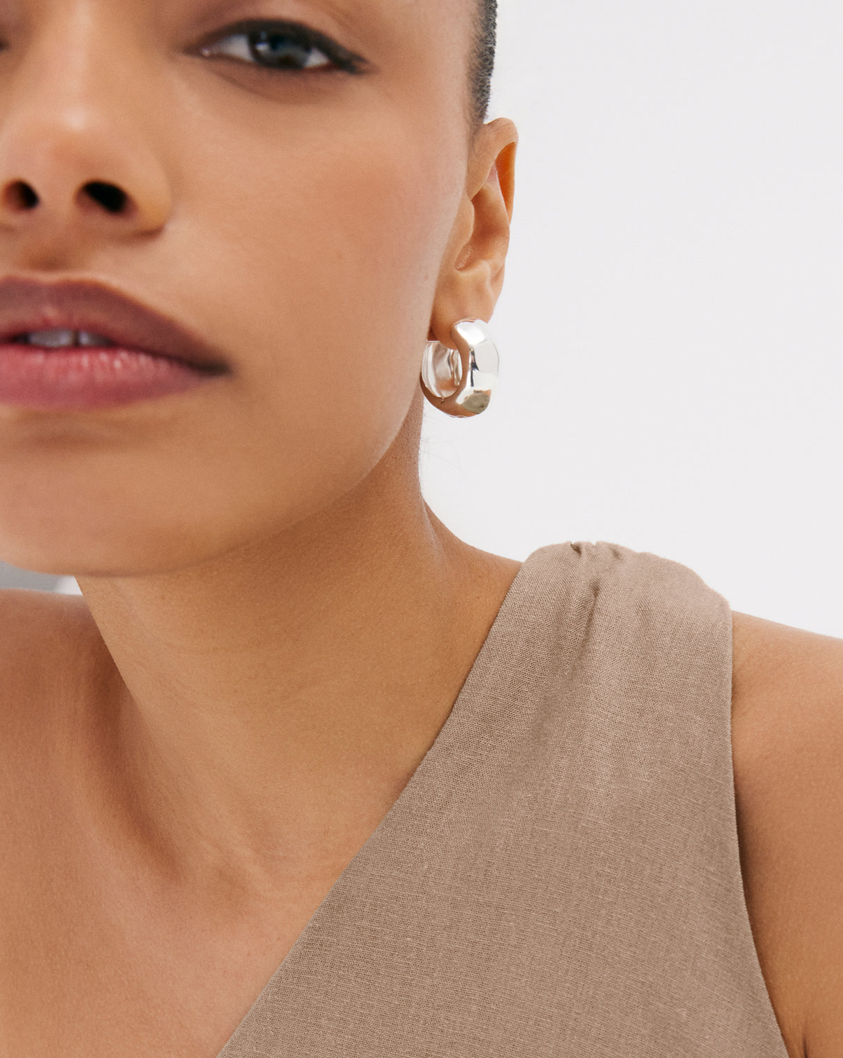 Model wearing sterling silver hammered hoop earrings, profile view showing how they frame the face and catch light