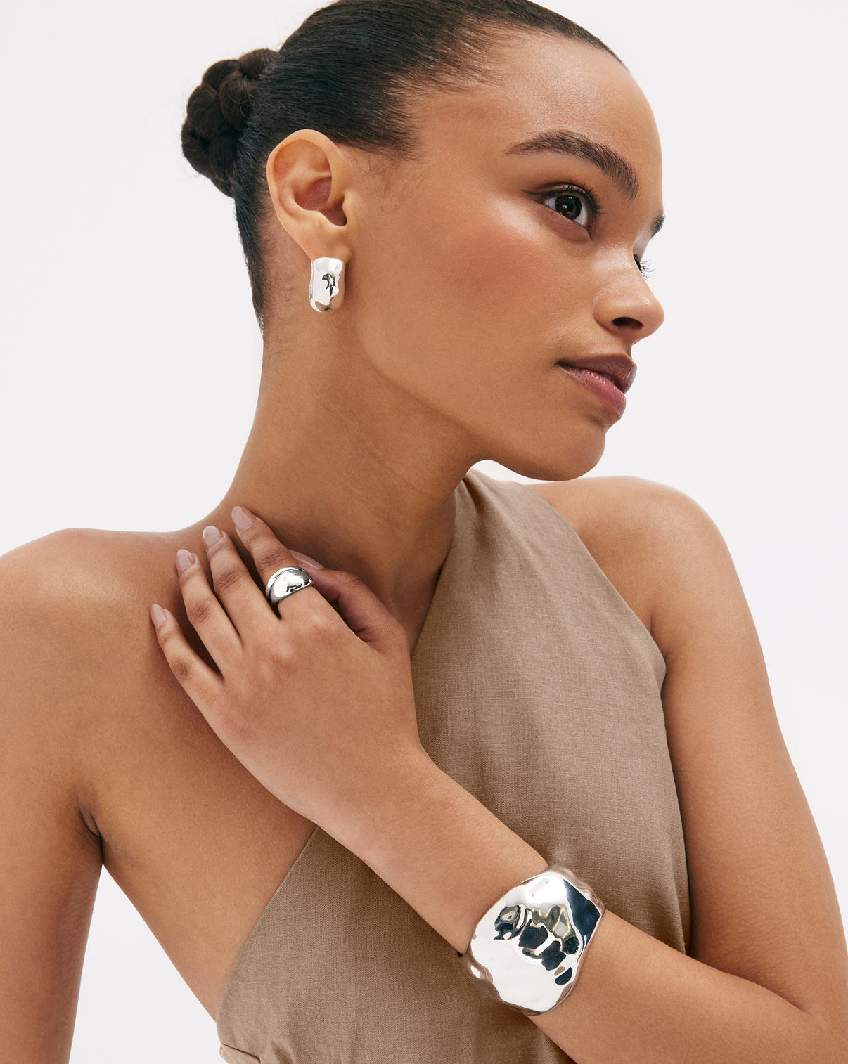 Close-up of model wearing sterling silver hammered styles, showcasing the earrings' size and proportion to ear