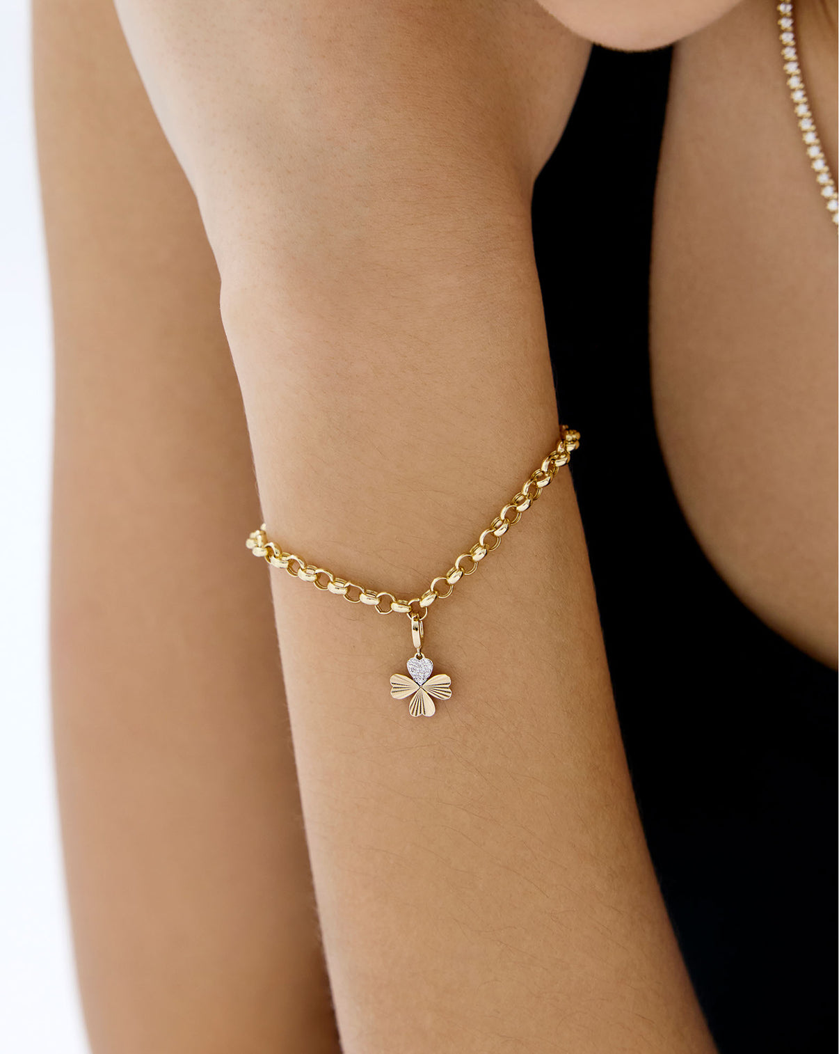 Clover charm on a gold bracelet worn on models wrist