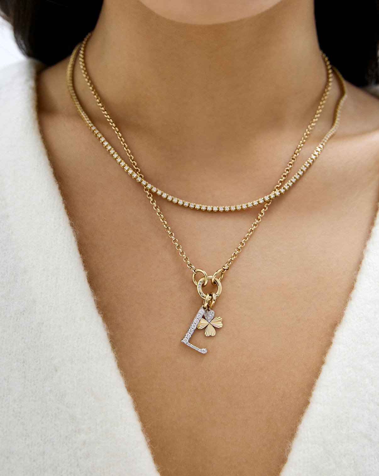 model wearing styled gold necklace with clover charm and initial letter pendant