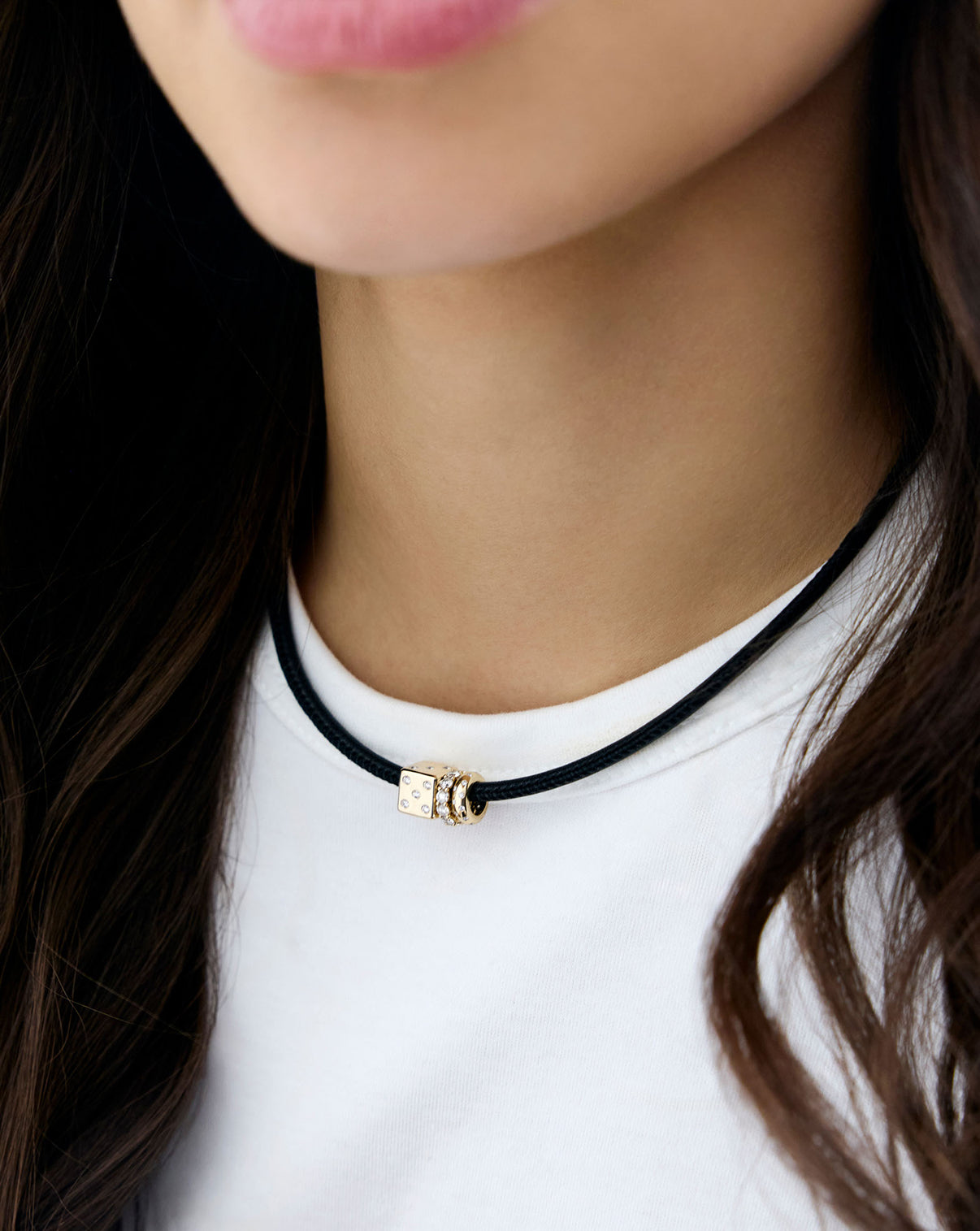 model wearing black leather cord necklace with diamond dice bead and other gold beads