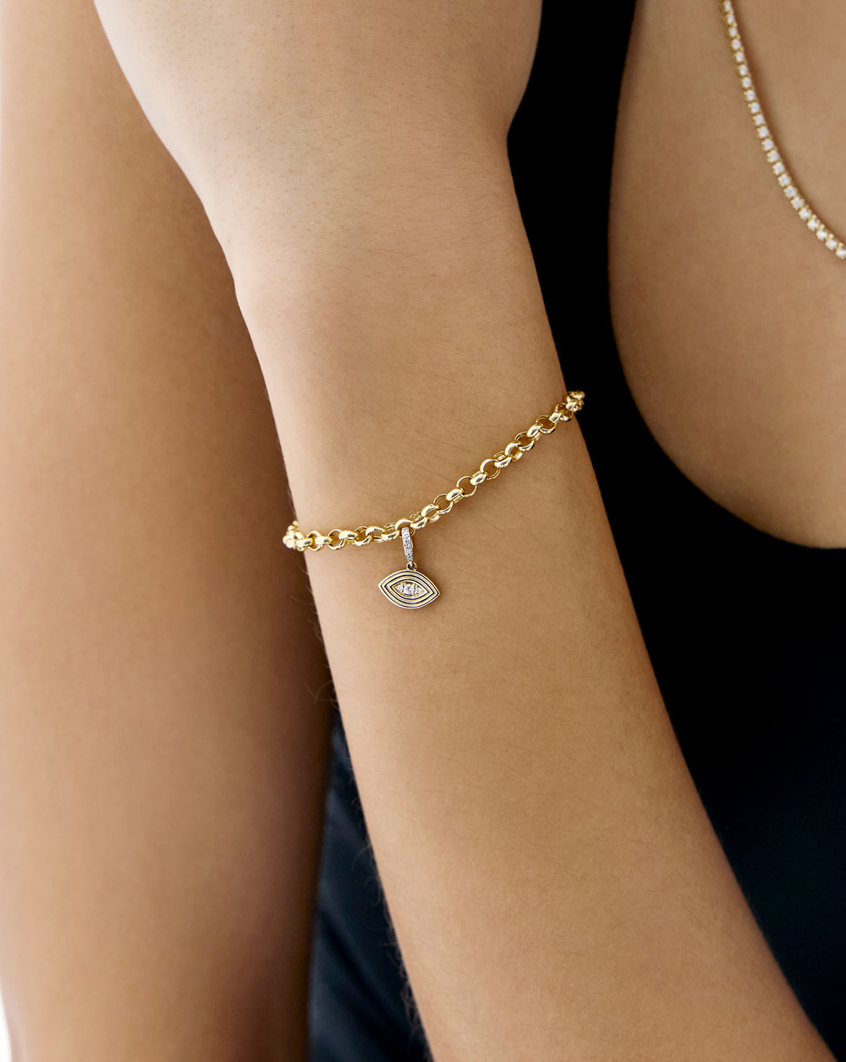 evil eye charm on a gold bracelet worn on models wrist
