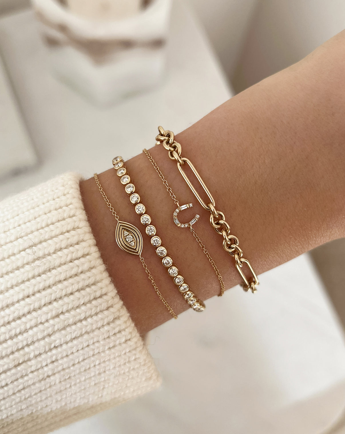 Horseshoe Bracelet in yellow gold shown on wrist with other bracelets