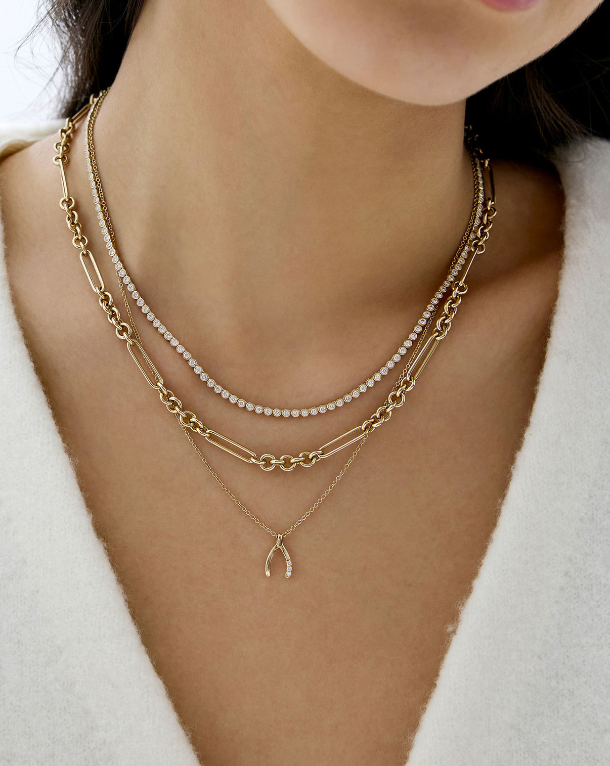 Wishbone necklace shown styled with other gold and tennis necklaces