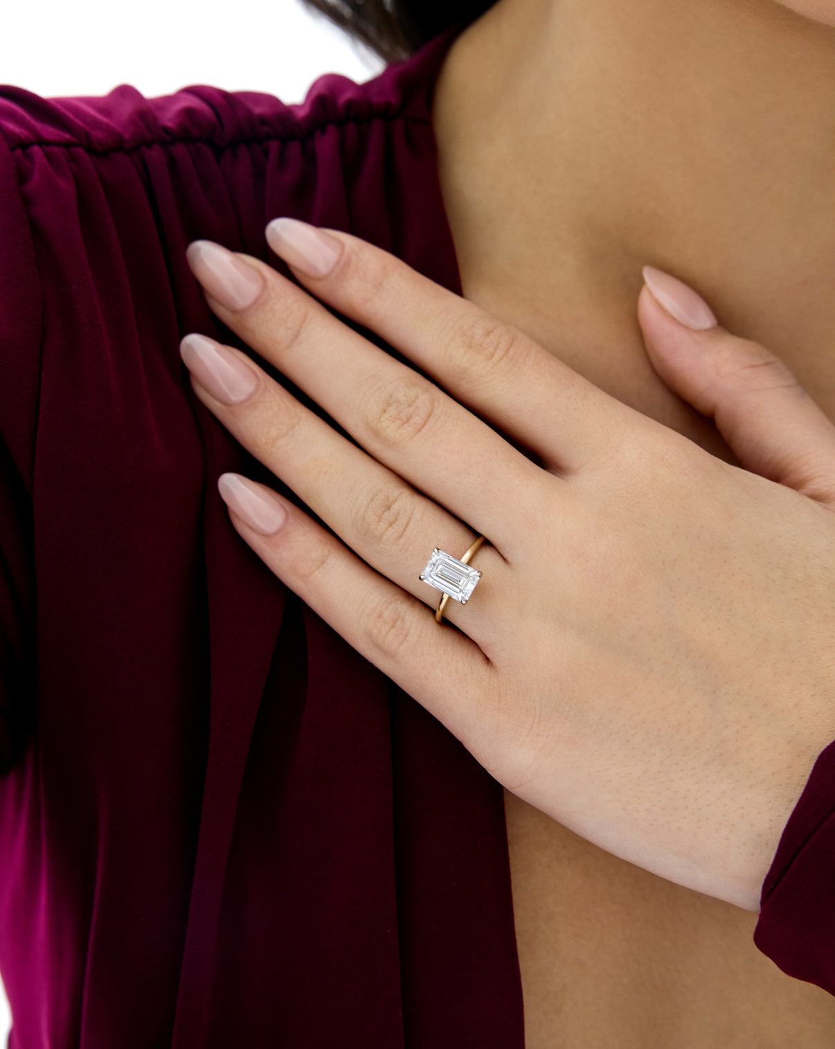 Close up of model wearing 3.06 carat Emerald ring of the 5.21 Emerald & Pear Whisper Thin® Duet diamond Engagement ring in 14K Yellow Gold