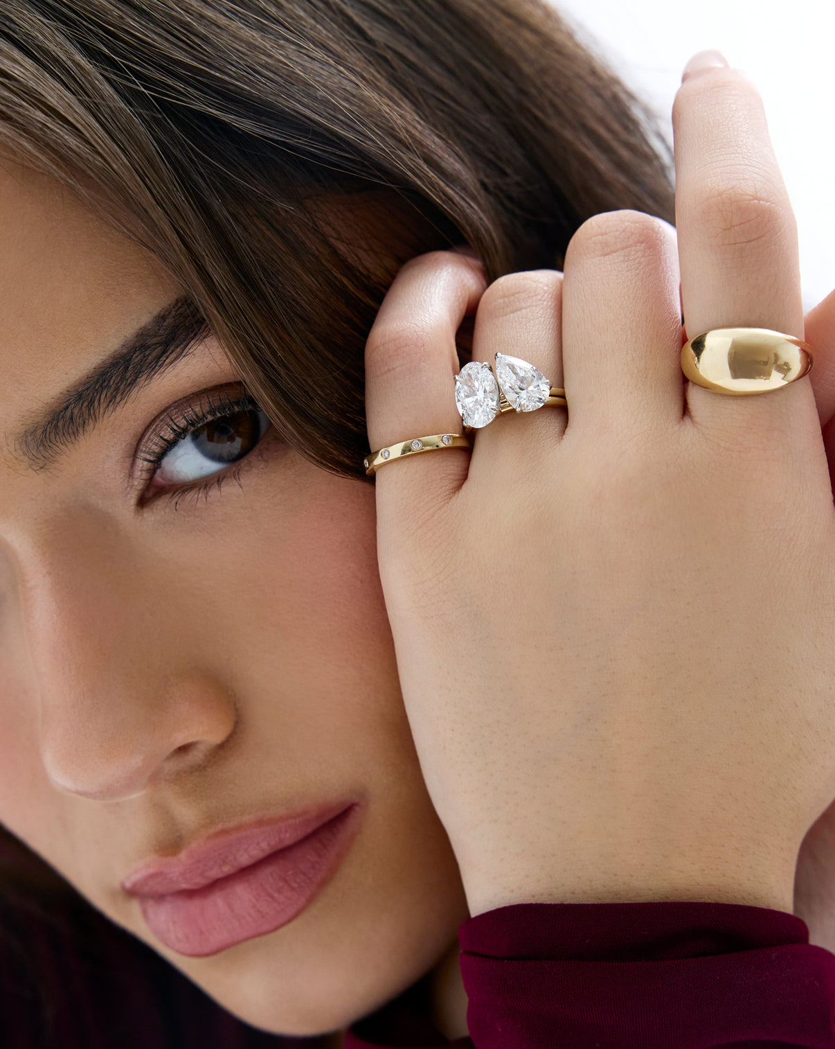 model wearing the stacked 4.70 Oval & Pear Whisper Thin® Duet diamond Engagement ring in 14K Yellow Gold with other diamond and gold jewelry on hand