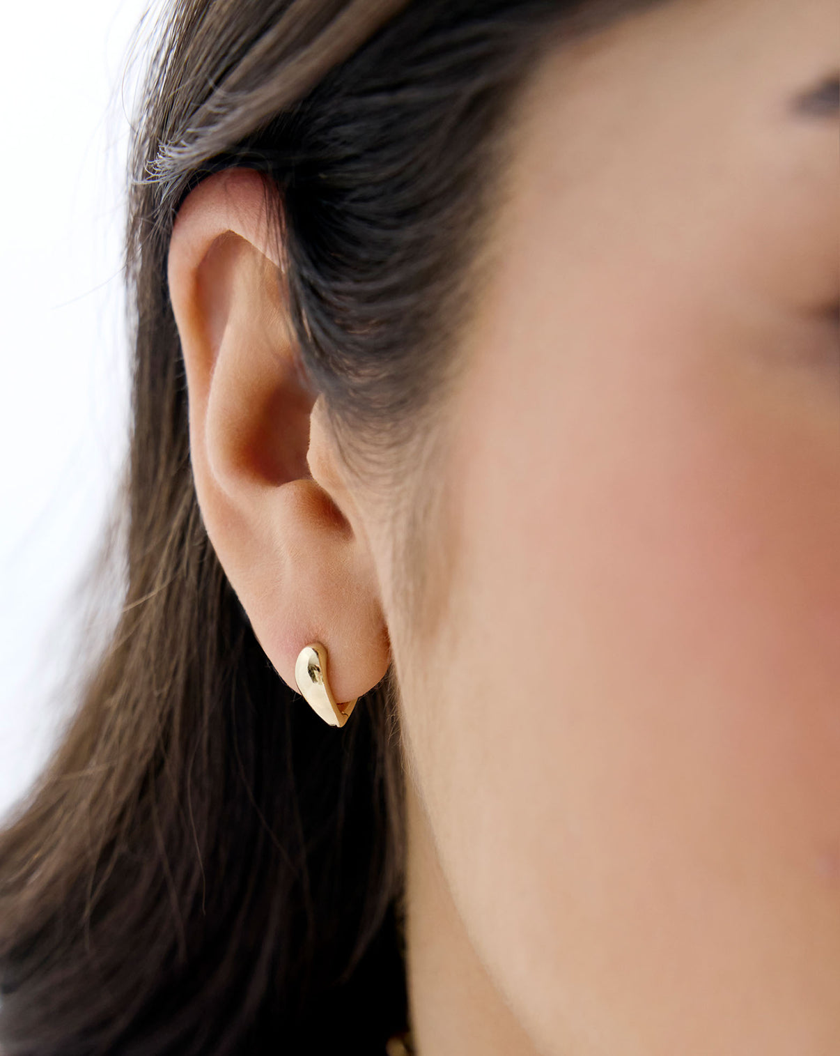 close up front view on model of 14K Yellow Gold Heart Huggie Earrings