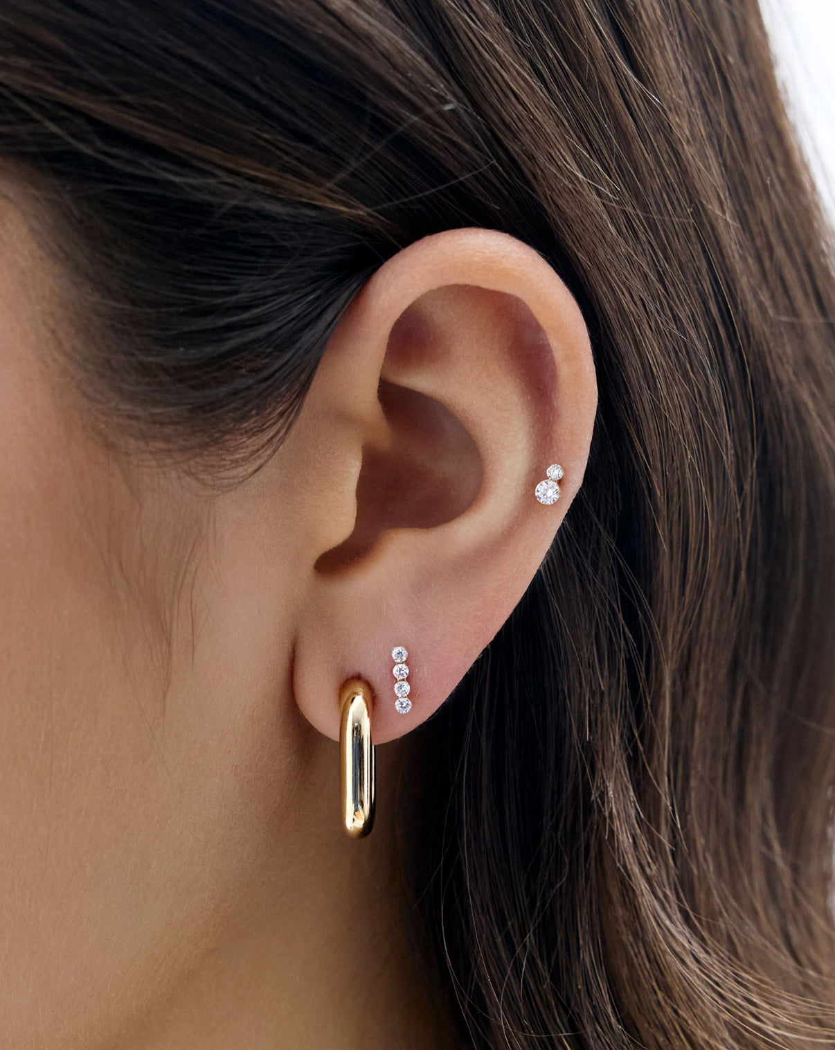 Close up image of model's ear, wearing the Duo Lab Diamond Flatback earring and styled with a gold link earring and the 4-Lab Diamond Flatback Earring 