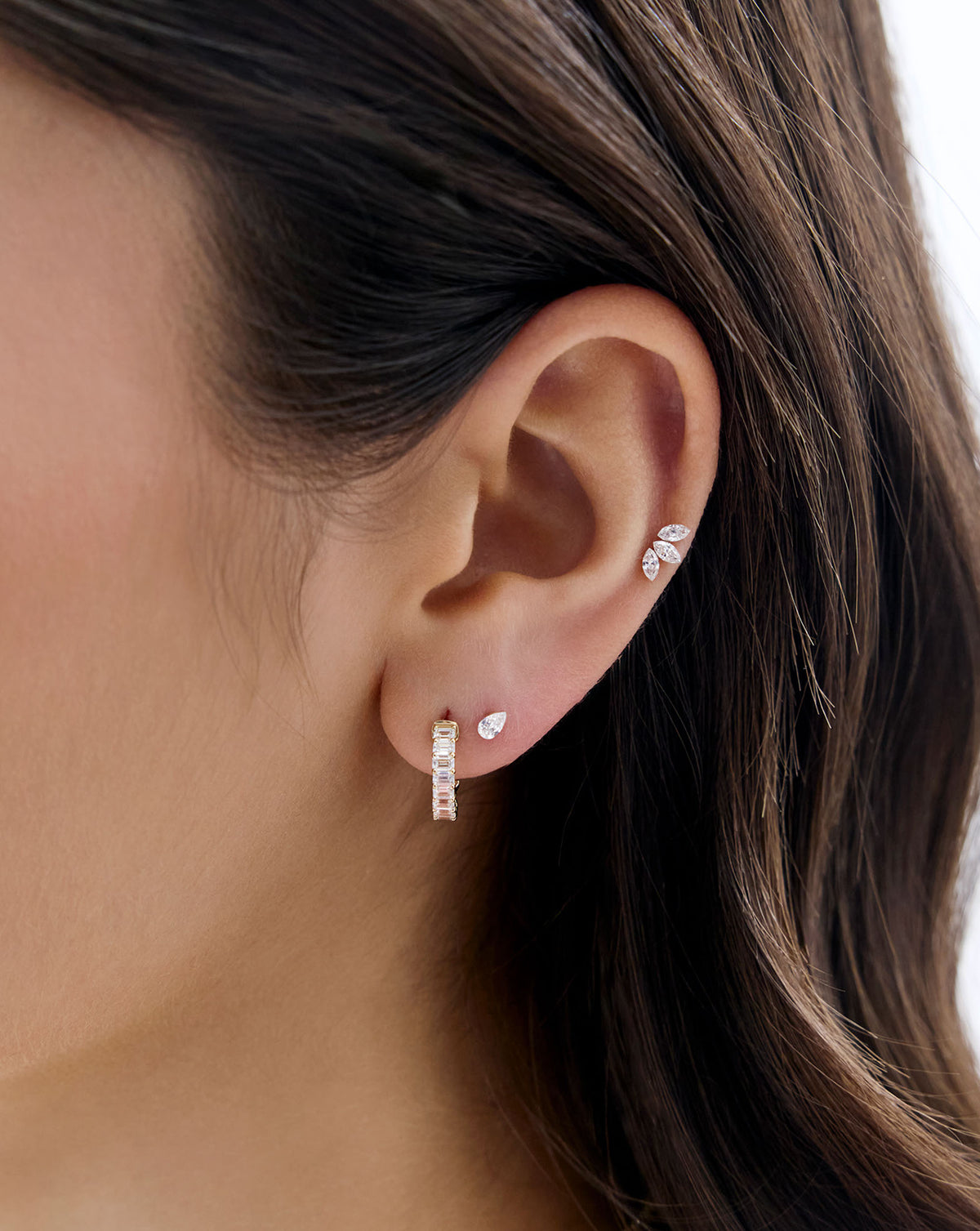 Close up image of model's ear, wearing the Mini Pear Lab Diamond flatback earring and styled with a diamond huggie and the marquise lab diamond flatback earring