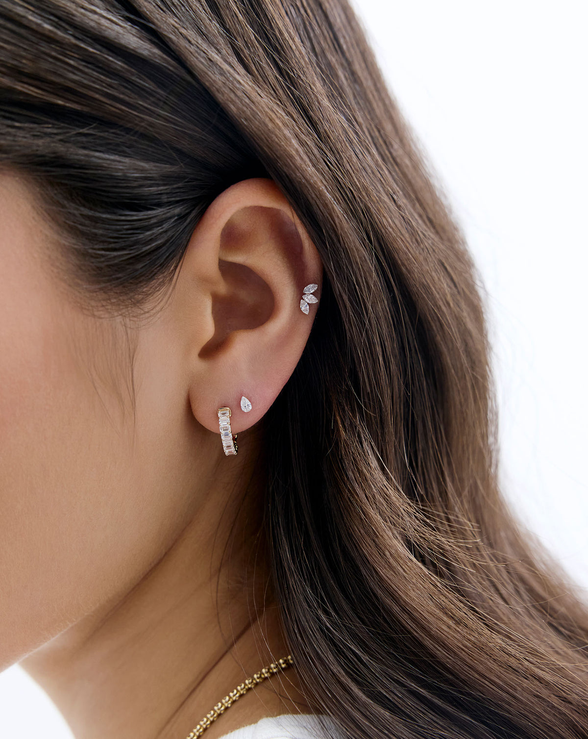 A model wearing the Mini Pear Lab Diamond flatback earring and styled with a diamond huggie and the marquise lab diamond flatback earring