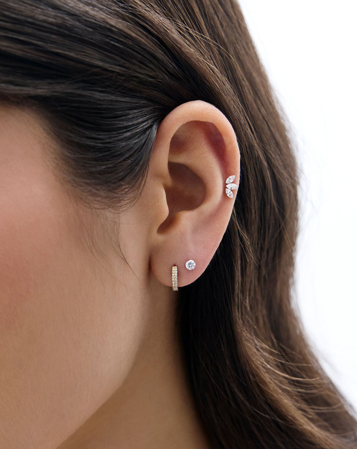 Close up image of model's ear, wearing the Mini Round Lab Diamond flatback earring and styled with a diamond huggie and the marquise lab diamond flatback earring