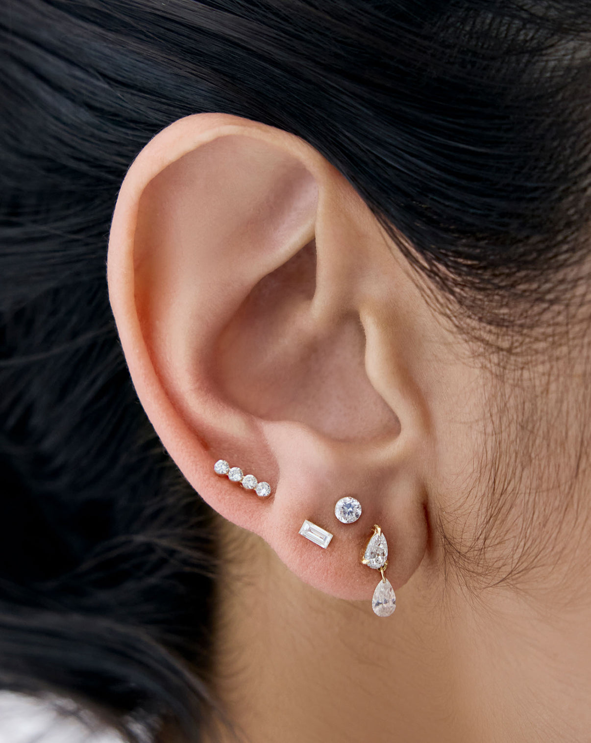 4 diamond flatback earrings shown close up on models ear: Pearl Drop, 4 Lab-Diamond, Mini Emerald, and Mini Round